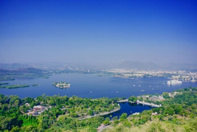 A breathtaking aerial view of Lake Pichola surrounded by lush greenery and Udaipur's cityscape.