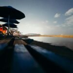 A tranquil beach view at twilight with rows of beach umbrellas and a serene ocean backdrop.