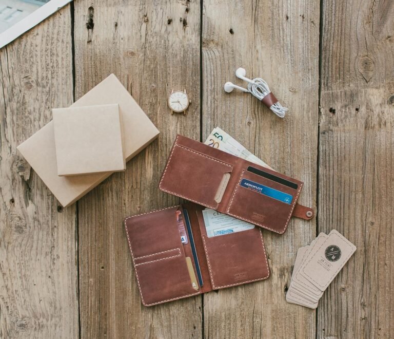 Brown leather wallet with cash, cards, and a watch on a rustic wooden background.