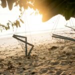 a couple of swings sitting on top of a sandy beach