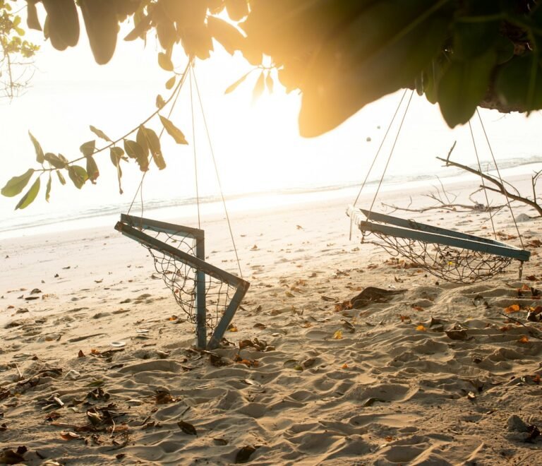 a couple of swings sitting on top of a sandy beach