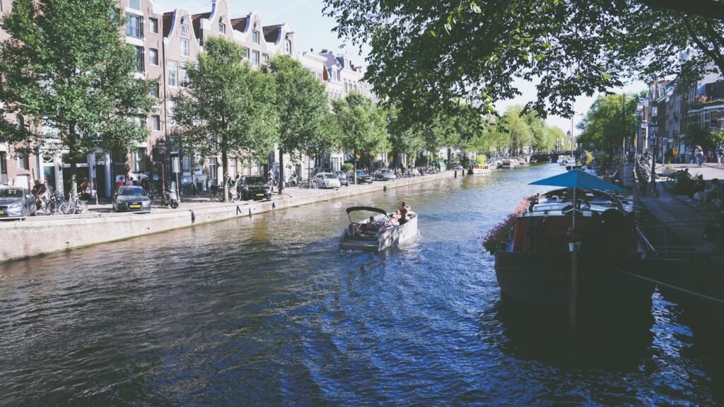 a couple of people on a boat in a canal with buildings and trees