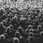 grayscale photo of people sitting on chair