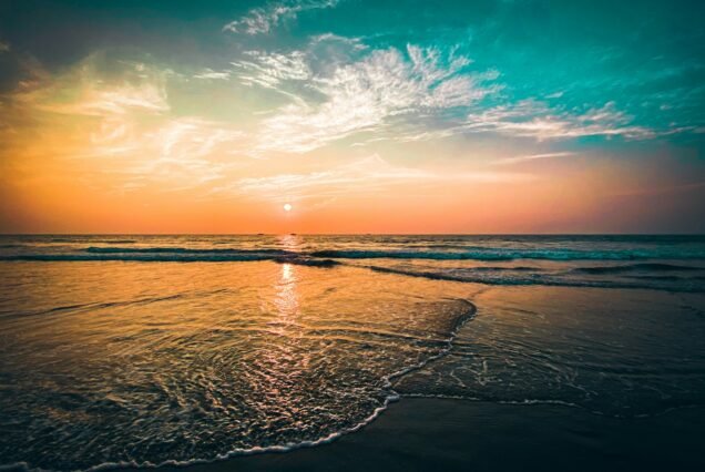 the sun is setting over the ocean on the beach